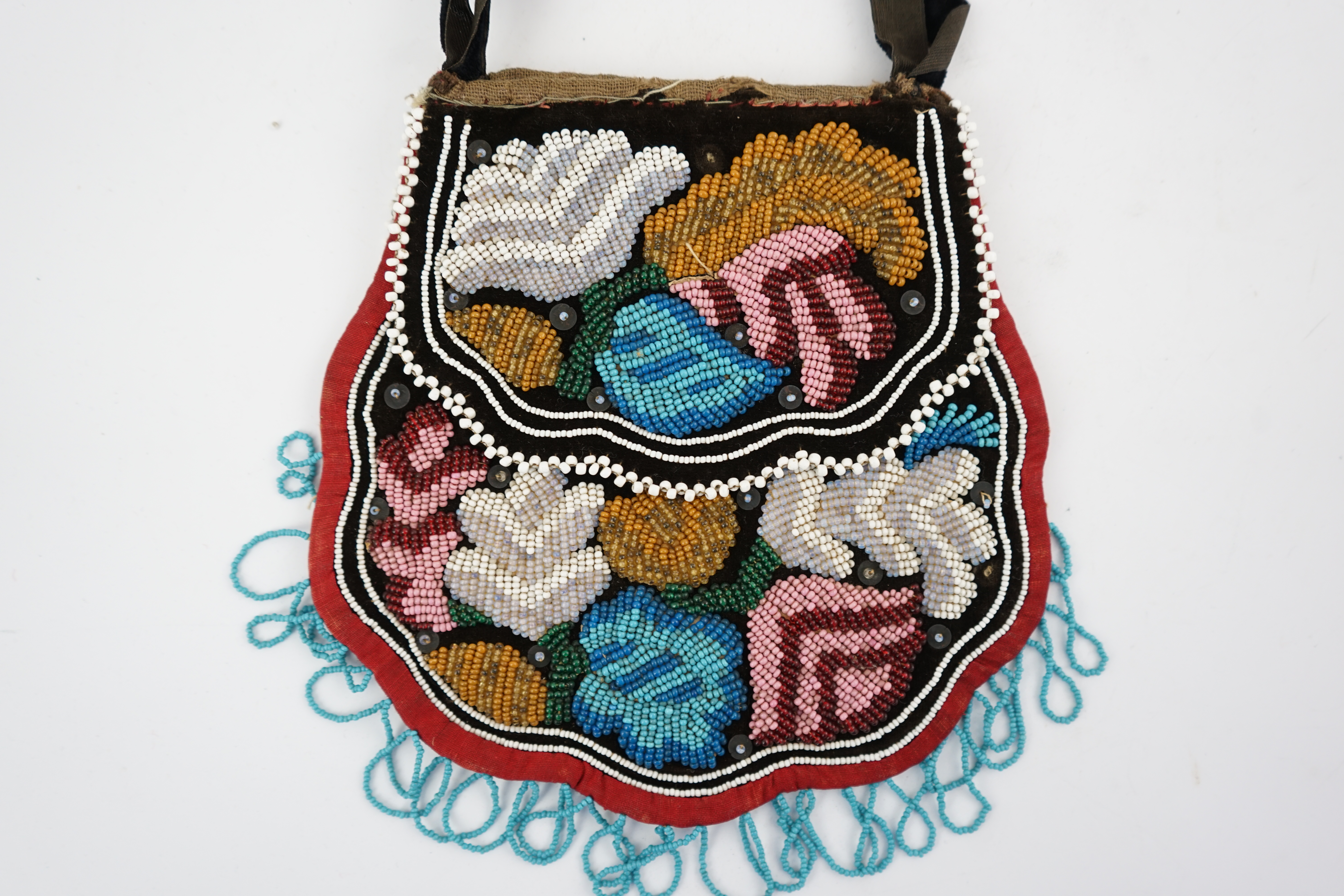 A 19th century Iroquois Native American beaded bag worked in a tightly grouped pattern of multi-coloured beads, with flaps either side and small white bead borders, fringed a similar turquoise beads. 16cm high. Condition